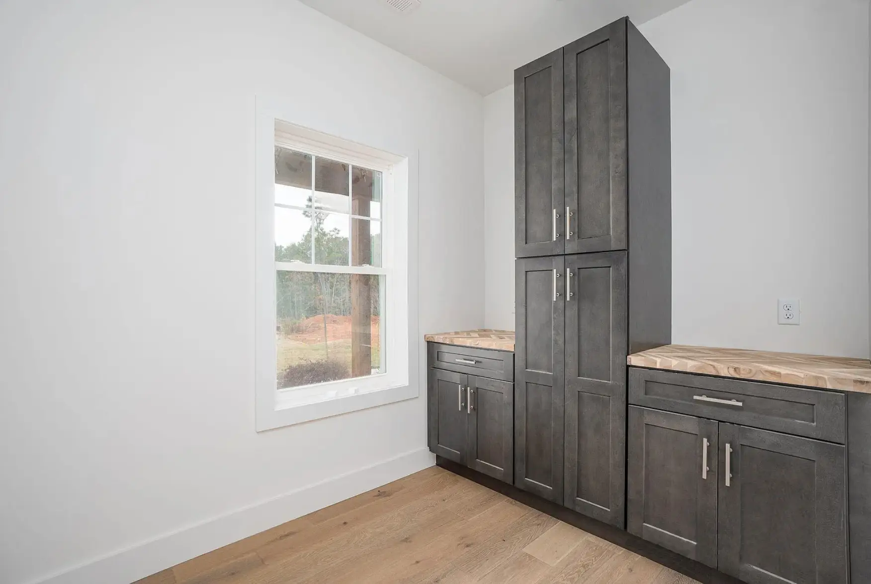 new construction home walk-in pantry with shaker style grey cabinets, hardwood floors, butcher block countertops