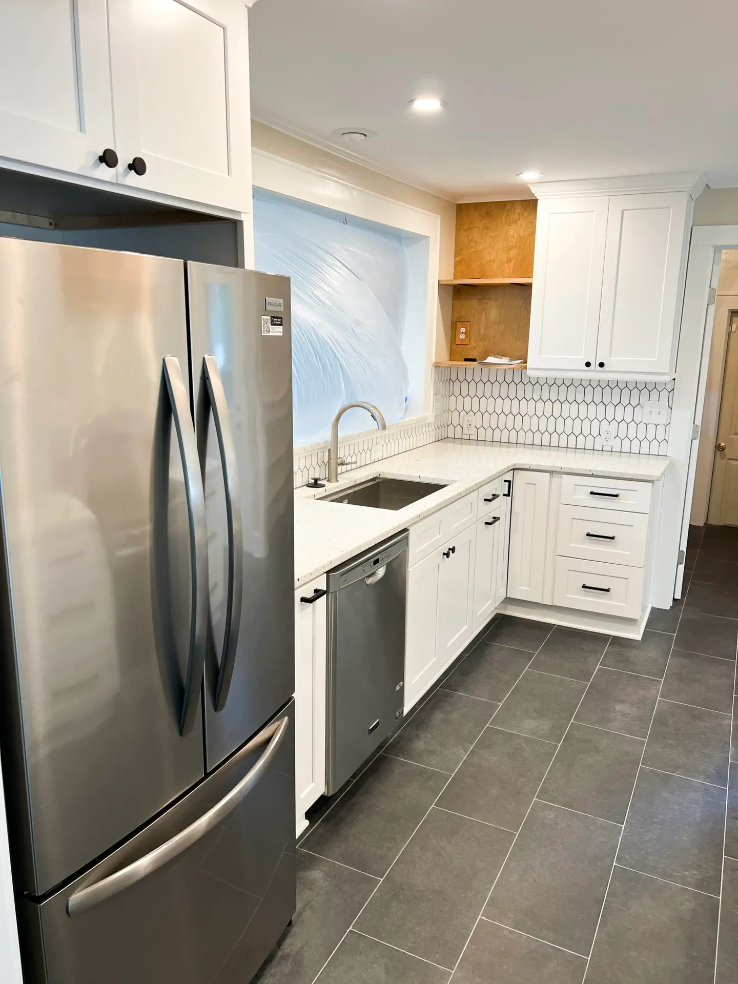 kitchen remodel with white shaker cabinets, white quartz countertops, brown cabinet hood, stainless steel appliances, white tile backsplash