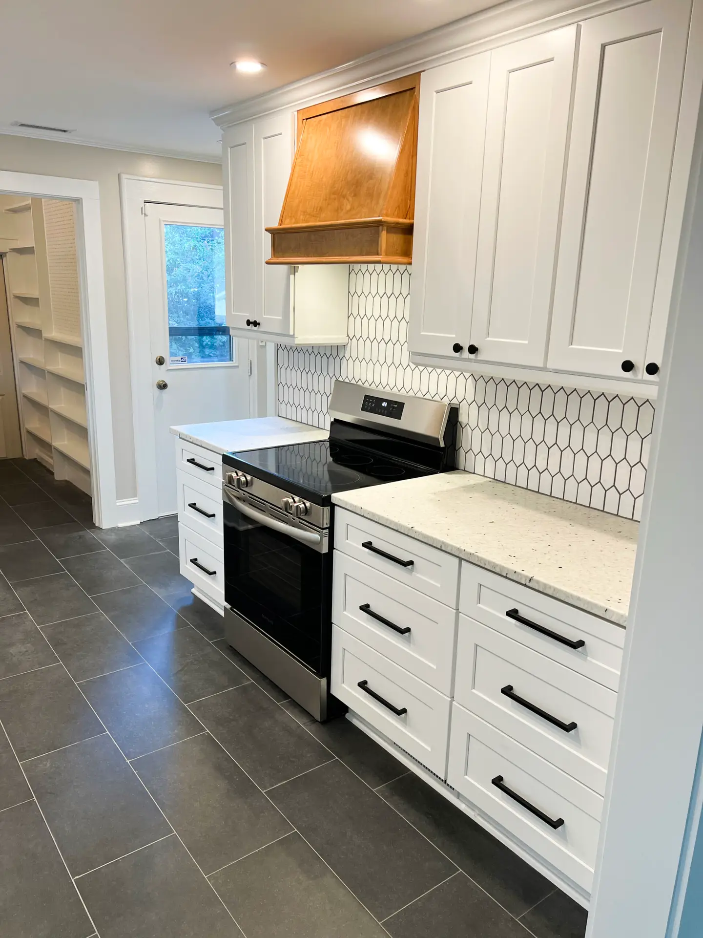 kitchen remodel with white shaker cabinets, white quartz countertops, brown cabinet hood, stainless steel appliances, white tile backsplash